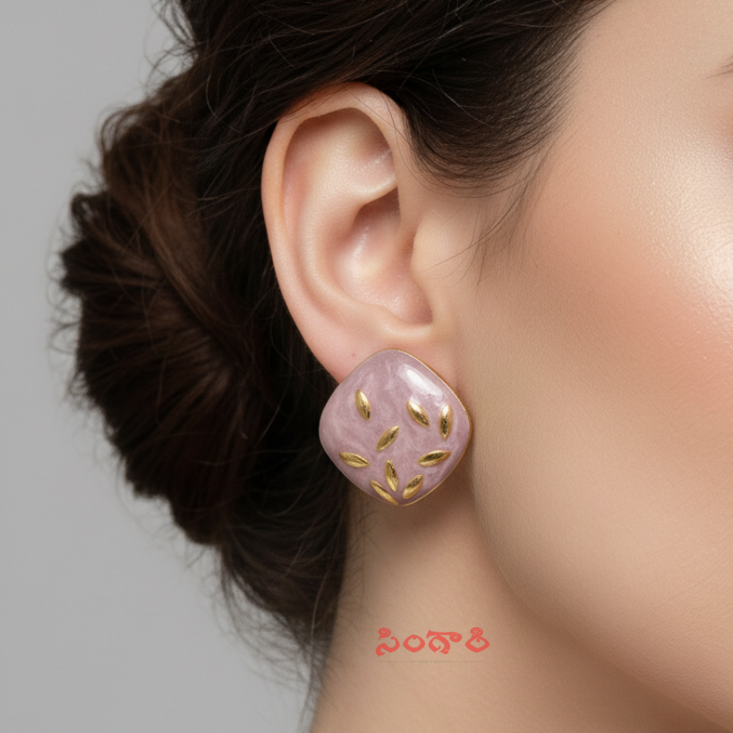 Close-up of a pink earring with gold accents on an ear against a neutral background