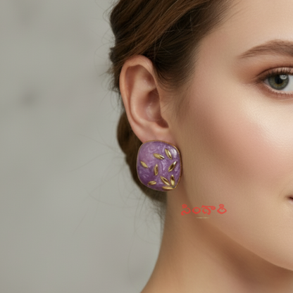 Close-up of a woman wearing a purple earring with gold accents against a neutral background
