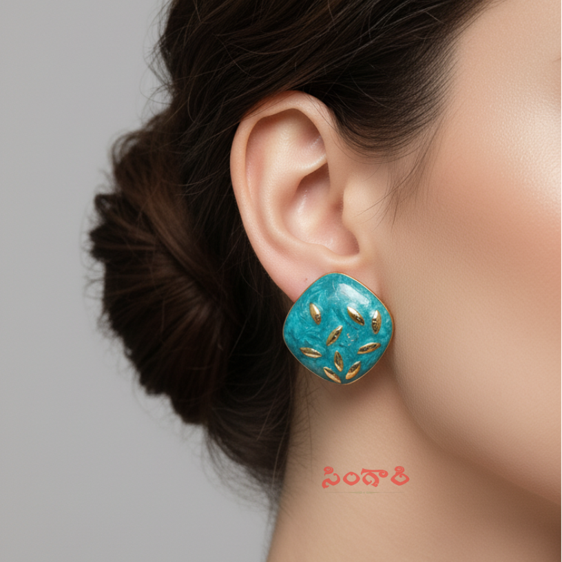 Turquoise earrings with gold accents worn by a model on a gray background