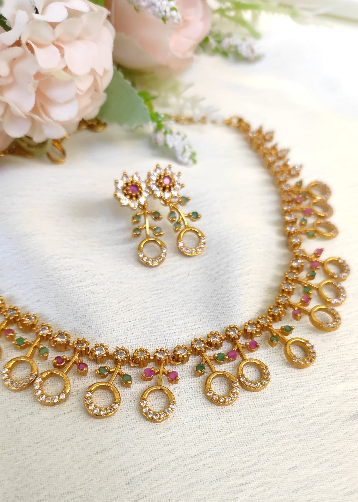 American diamond necklace and matching earrings set adorned with small multicolored ruby and emerald-like stones