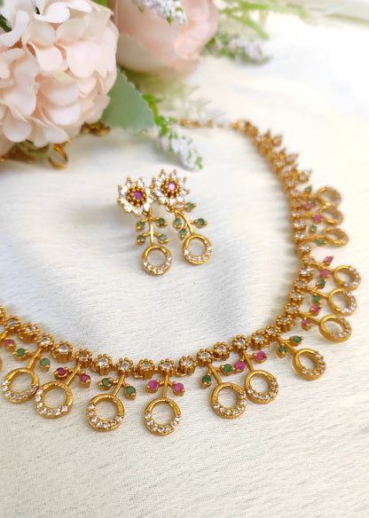 American diamond necklace and matching earrings set adorned with small multicolored ruby and emerald-like stones