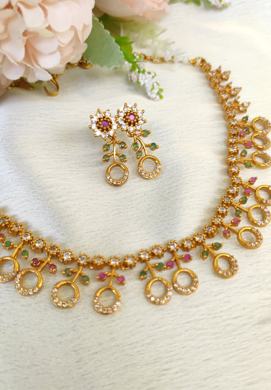 American diamond necklace and matching earrings set adorned with small multicolored ruby and emerald-like stones
