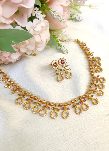 American diamond necklace and matching earrings set adorned with small multicolored ruby and emerald-like stones